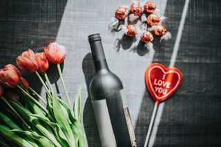 Valentine's bundle with some pink tulips, a bottle of wine, some lindor chocolate and a red heart-shaped lolly pop that says 'I LOVE YOU'