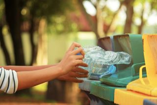 Recycling facts: A woman puts a plastic bottle in a recycling bin