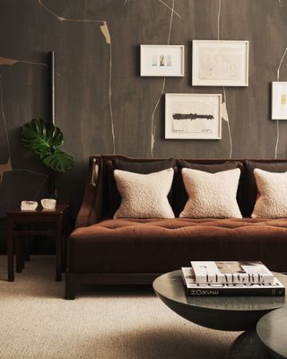 A living room with wood-effect wall panels, a brown velvet sofa, and taupe carpet