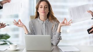 Calm female executive meditating in front of a laptop