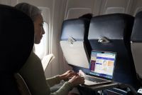 Woman using a MacBook Air on an airplane.