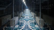 Prada A/W 2025 menswear runway show set featuring scaffolding and patterned carpet