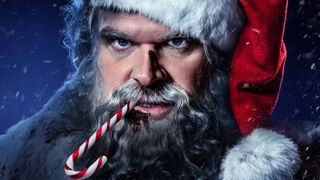David Harbour's Santa stares into the camera with a candy cane in his mouth in Violent Night