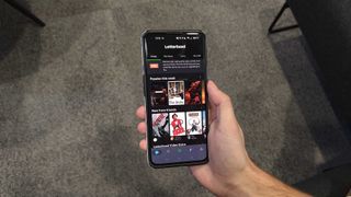 A hand holding a phone with the home page of Letterboxd displayed.