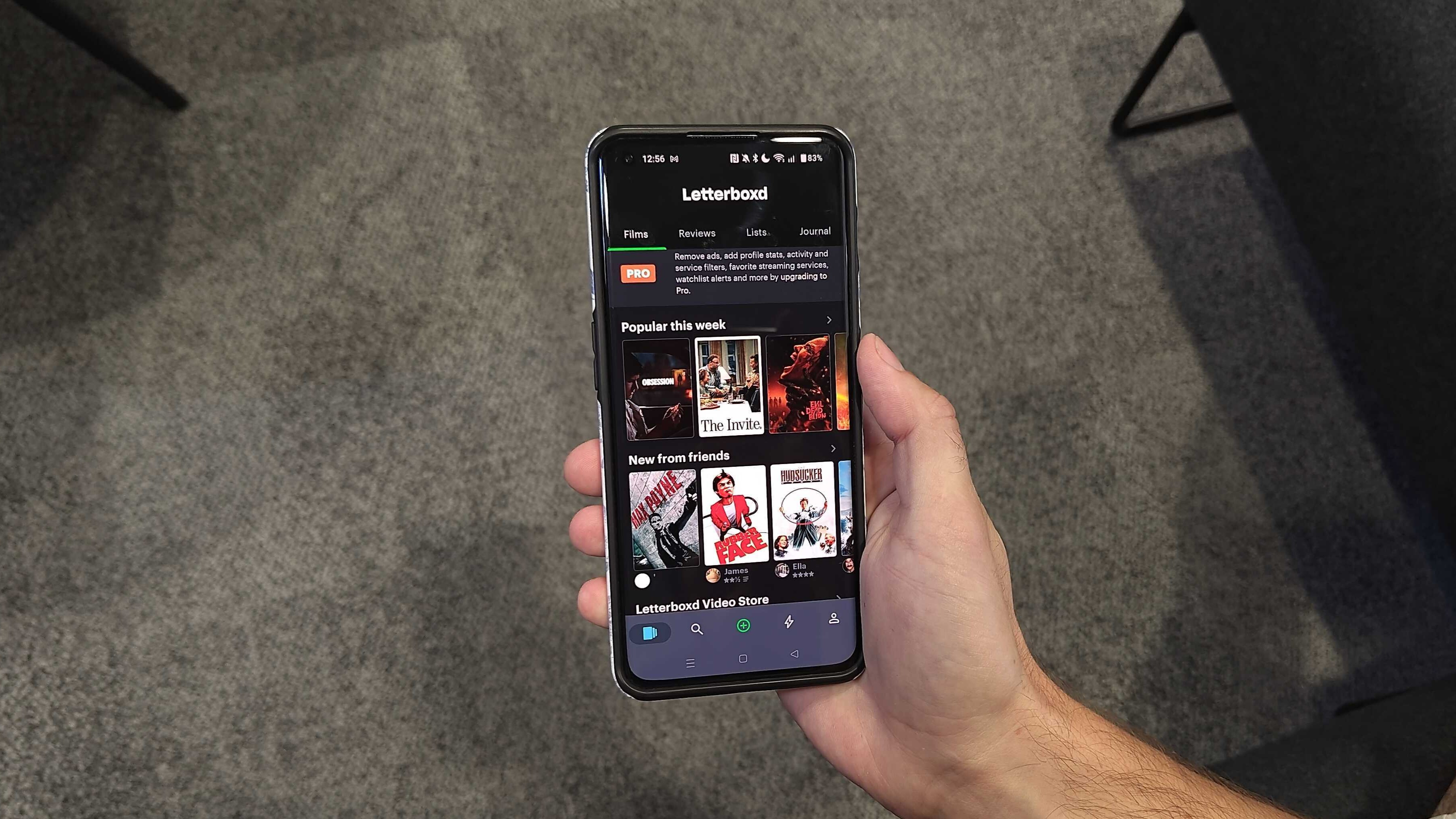A hand holding a phone with the home page of Letterboxd displayed.