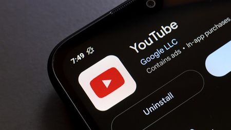 The YouTube app logo appears on the screen of a smartphone
