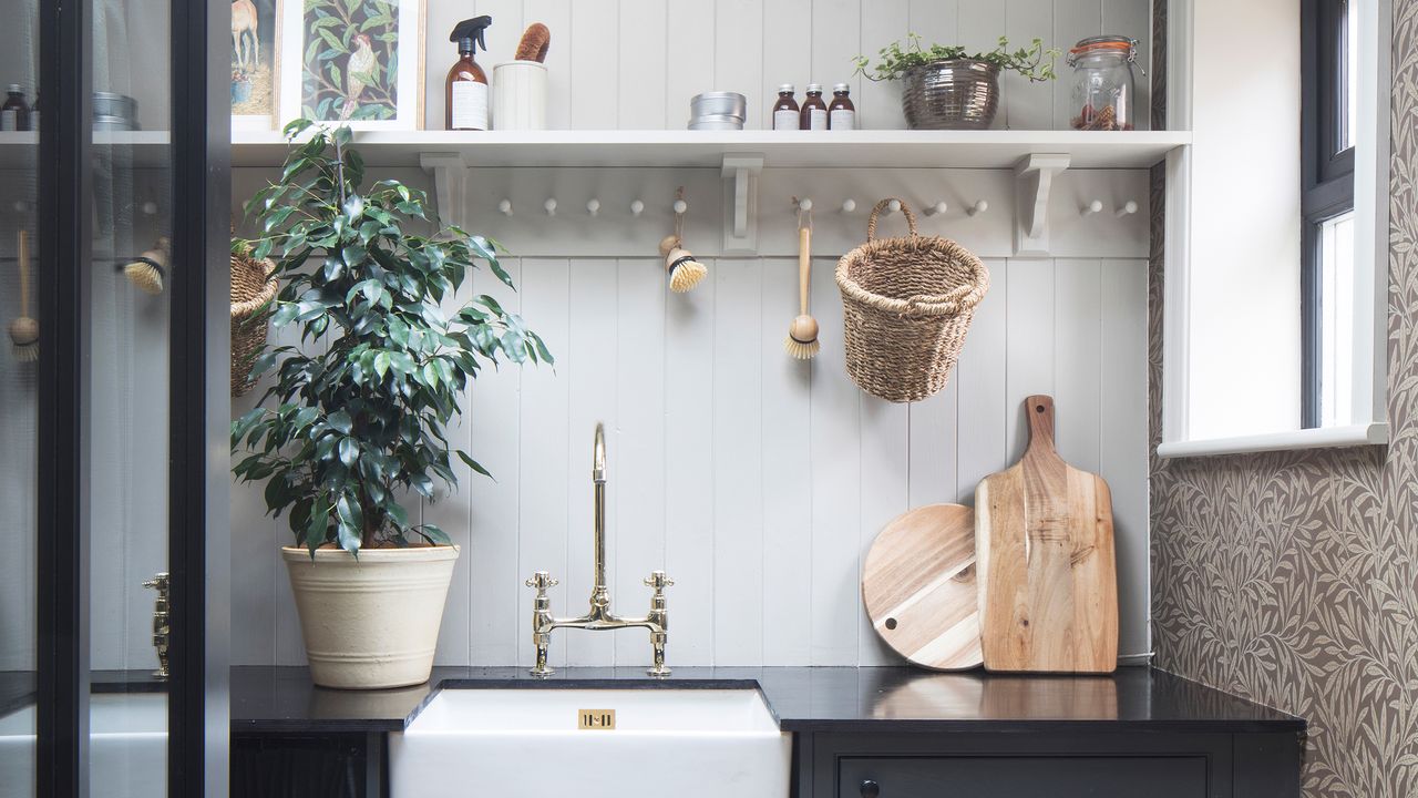 Laundry room with dark grey cabinetry, Belfast sink, wall panelling and wallpaper