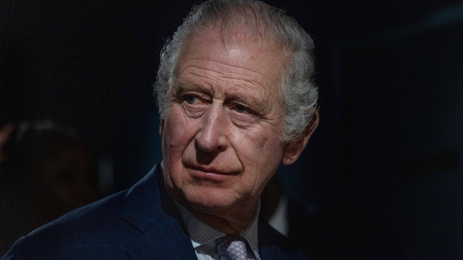 King Charles looks serious as he stares while wearing a suit