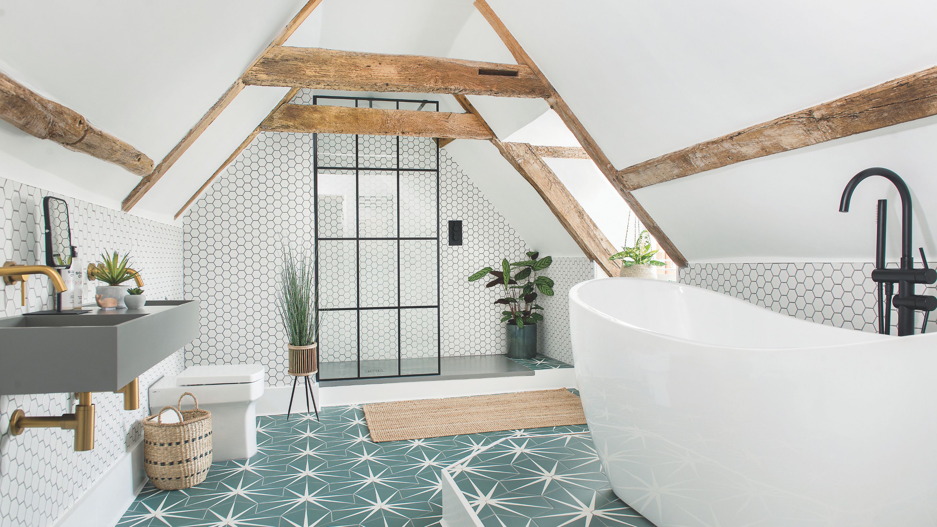 Attic bathroom with blue star tiled flooring, a freestanding bath and a shower area at the back of the room