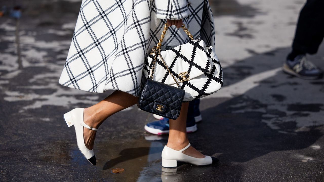 A guest at Paris Fashion Week crossing the road holding a checkered Chanel bag