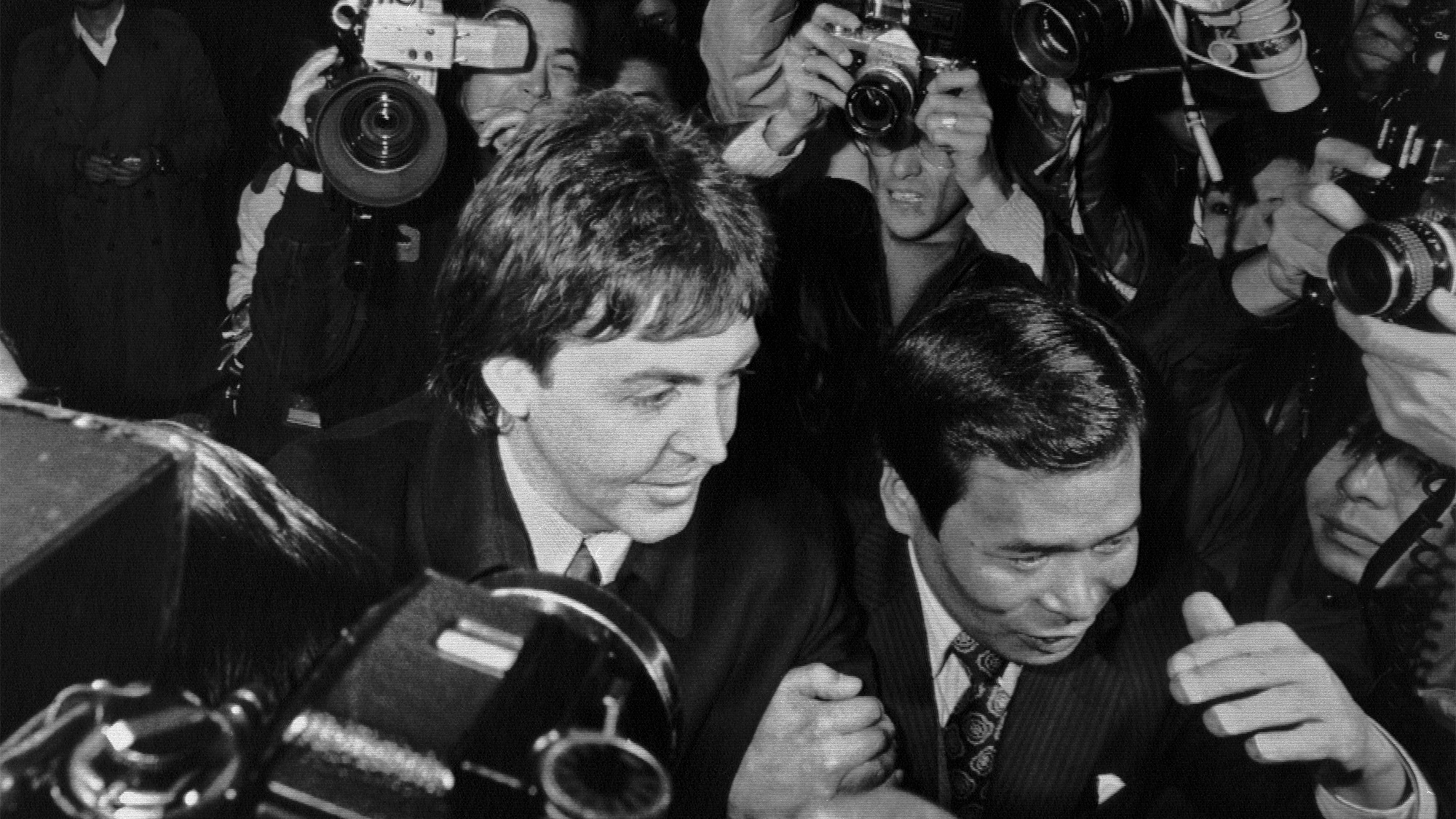 (Original Caption) Surrounded by press photographers, The Wings&#039; leader Paul McCartney enters the narcotics control office of the Health and Welfare Ministry 1/16 after he was arrested for allegedly bringing in over 200 grams of marijuana into Japan, police said.