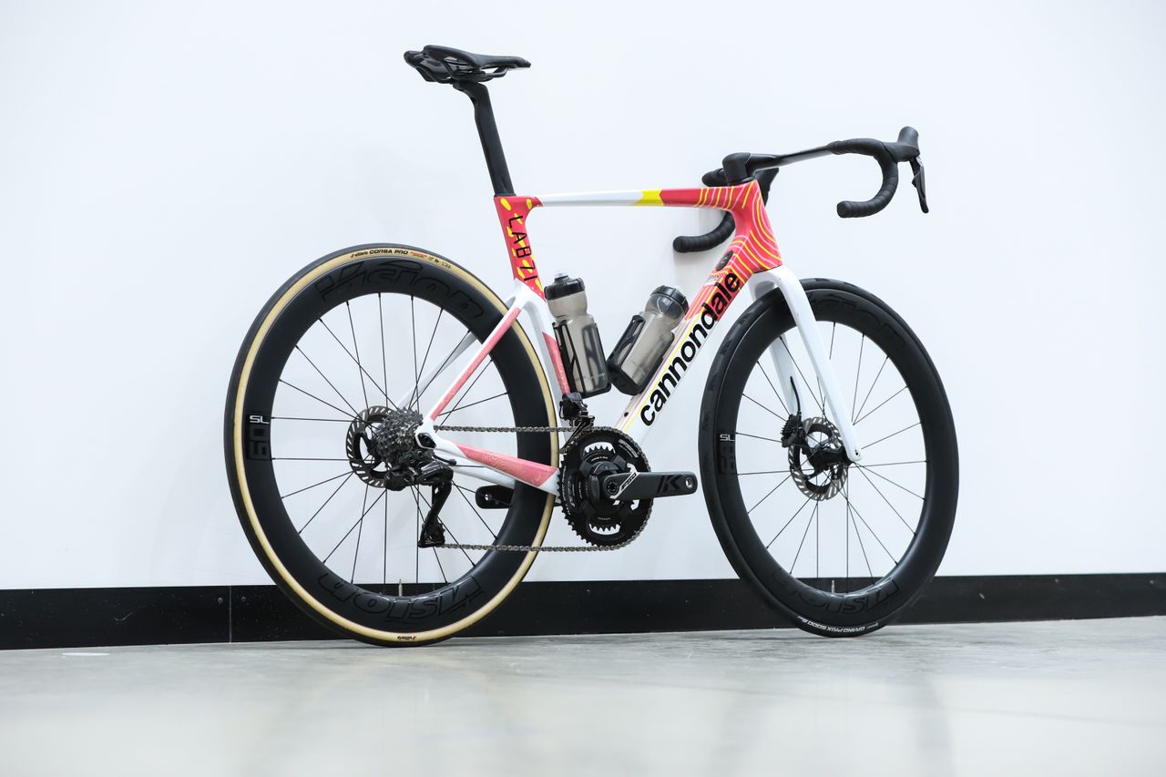 A team-edition Cannondale SuperSix Evo 4 stands against a white wall