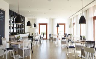 Dining area, black and white chairs and matching lampshades hanging from ceiling