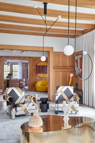 contemporary living room with brown paneling and colorful upholstered armchairs