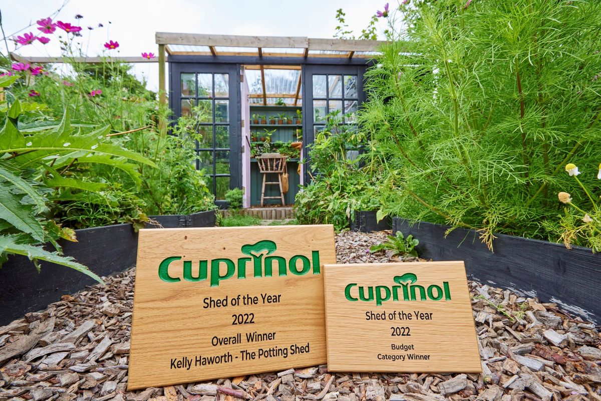 The winning shed of the 2022 Cuprinol Shed of the Year, with the award made of wood sitting on the floor in front of the shed