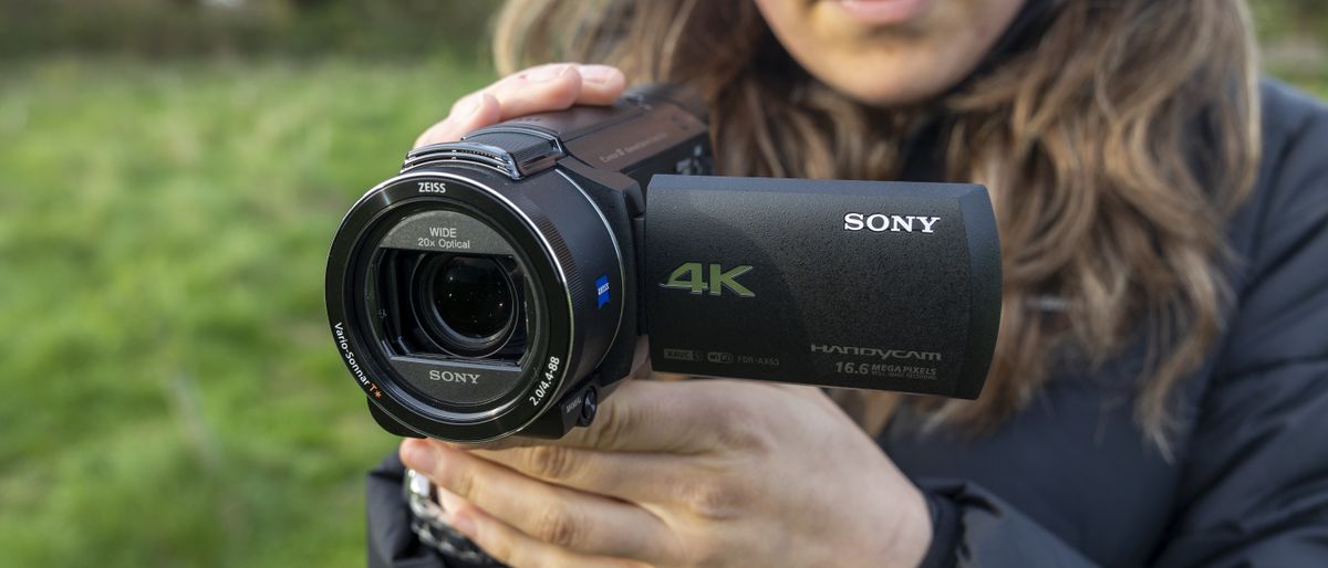 A front view of a photographer holding the Sony FDR-AX53 camcorder