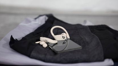 Powerbeats Pro Totally Wireless Earphones resting with phone on workout clothes