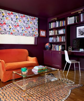 A purple painted living room with a red velvet sofa