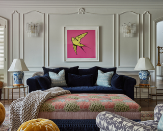 Navy blue plush couch with upholstered coffee table and bird art in fluorescent