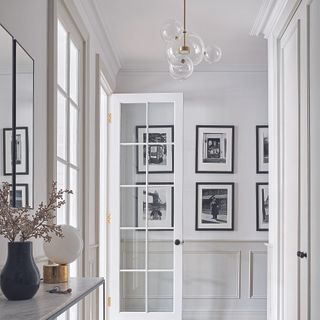 Hallway with photos in frames on wall and glass pendant light.