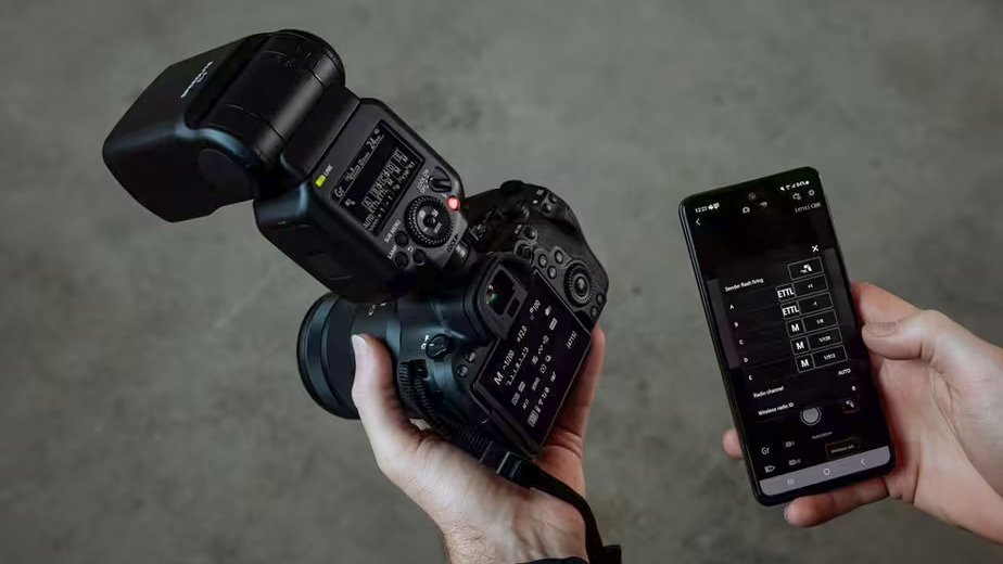 Canon EL-5 flashgun on camera being held in someone's hand, with a smartphone with the app in the other hand