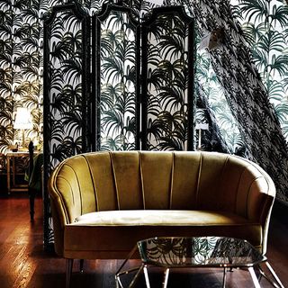 room with palm leaf printed wall and yellow sofaset