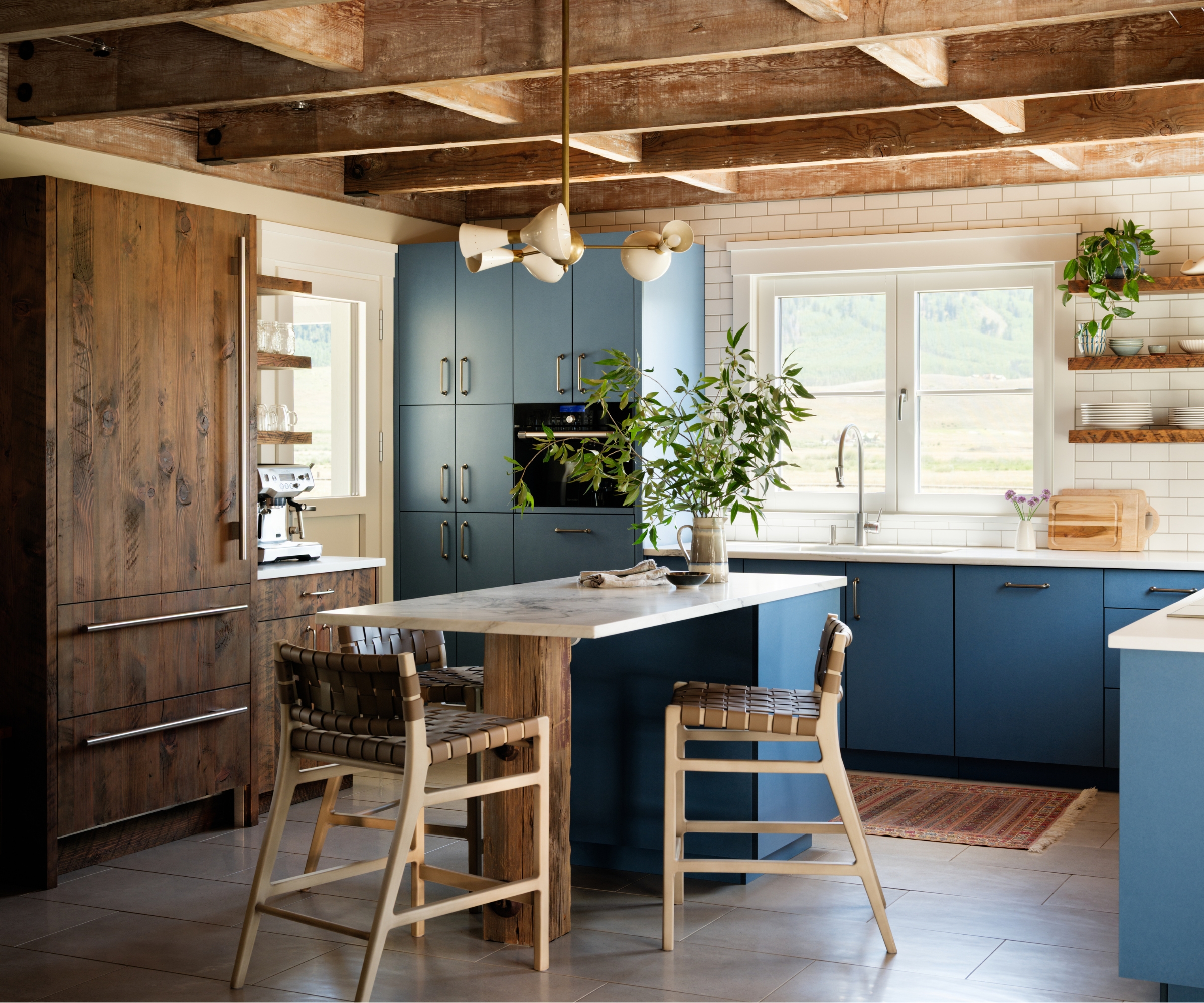 A U-shaped kitchen with mid-blue cabinets, rustic wood accents, and white countertops