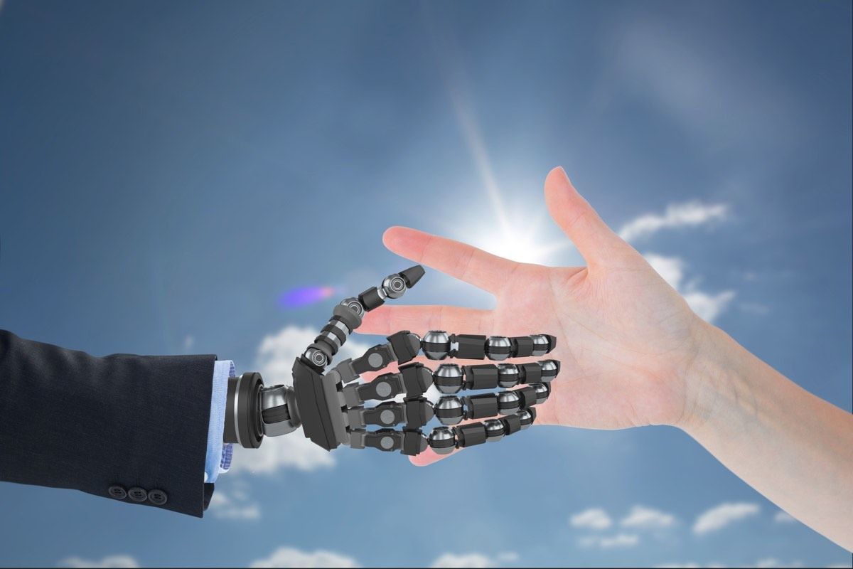 robot hand and human hand against sky background.