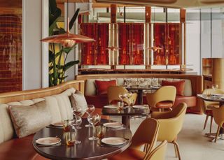 An amber and copper-shaded dining room with leather creme mid-century modern furniture.