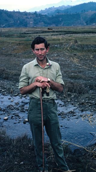 Portrait of Prince Charles, Prince of Wales (and future King Charles III) as he leans on a walking stick towards the end of a three-day trek in the foothills of the Himalayas, Nepal, December 11, 1980