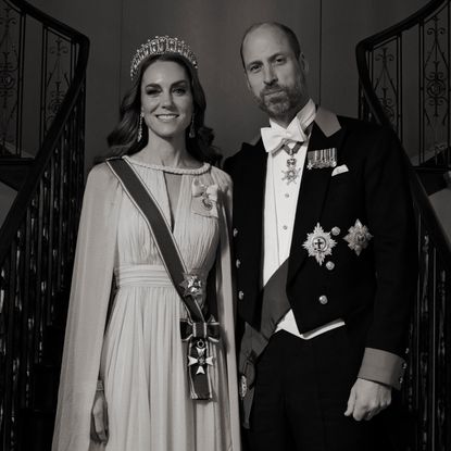 A black and white photo of Princess Kate and Prince William on a staircase in formalwear 