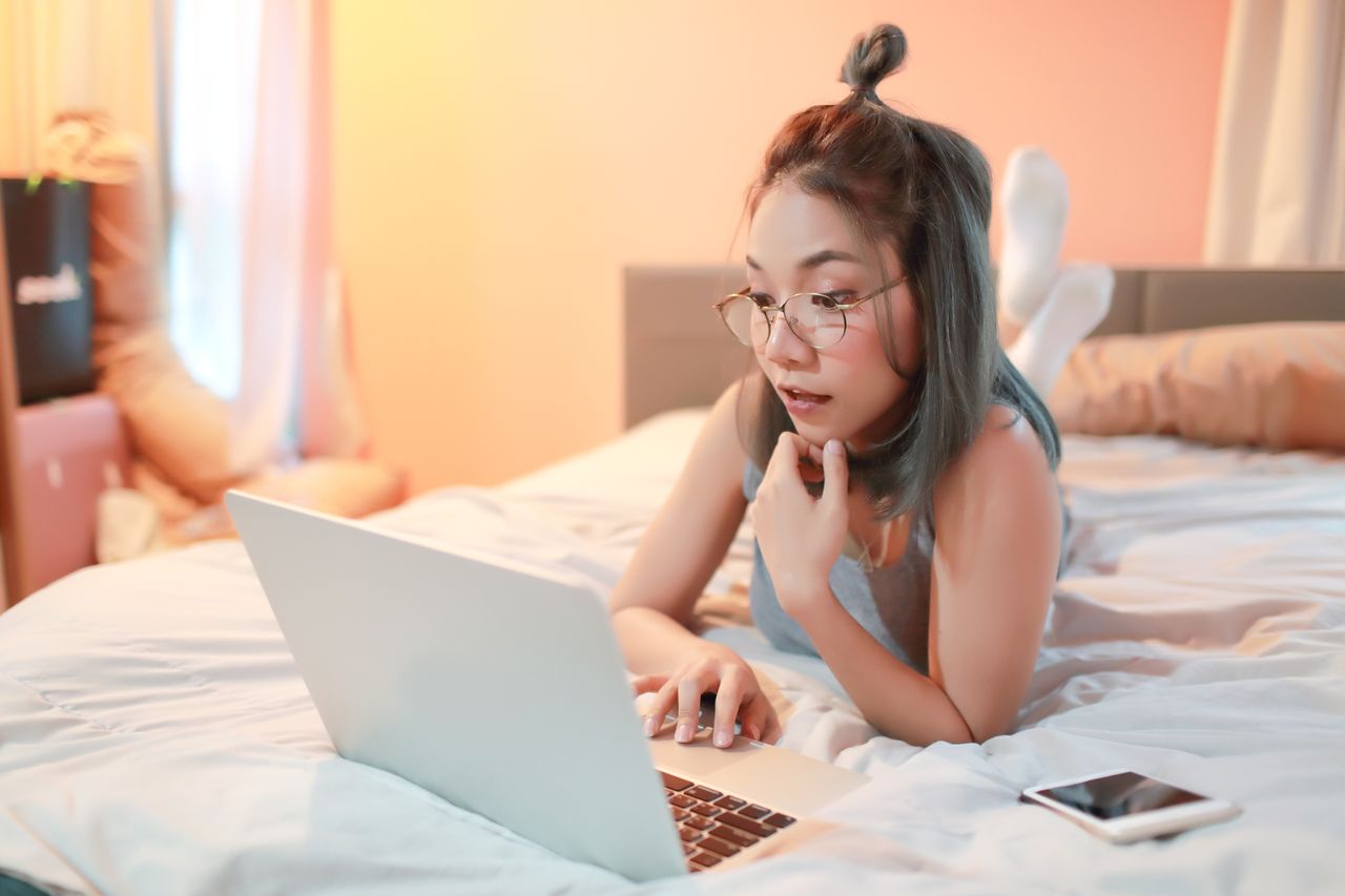 A woman watches ethical porn on her bed alone