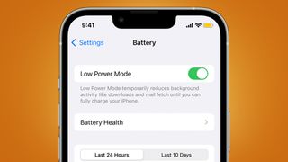 An iPhone on an orange background showing Low Power Mode in the settings