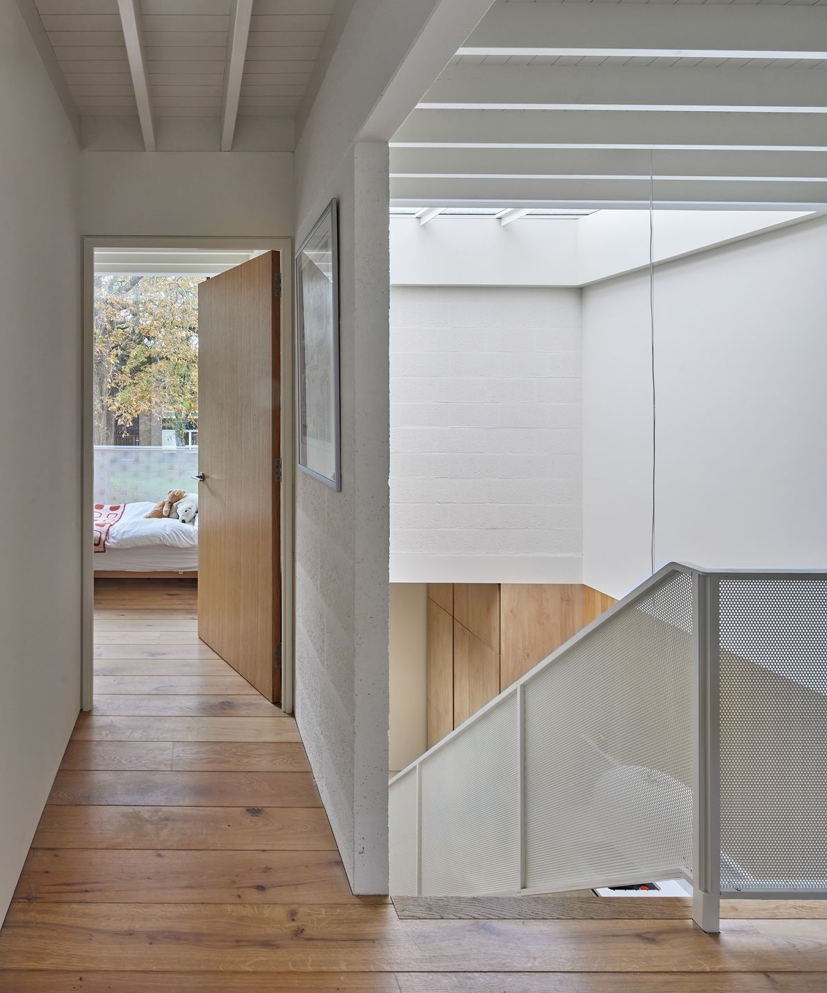 A landing with light oak wood flooring and view into a bedroom via an open door