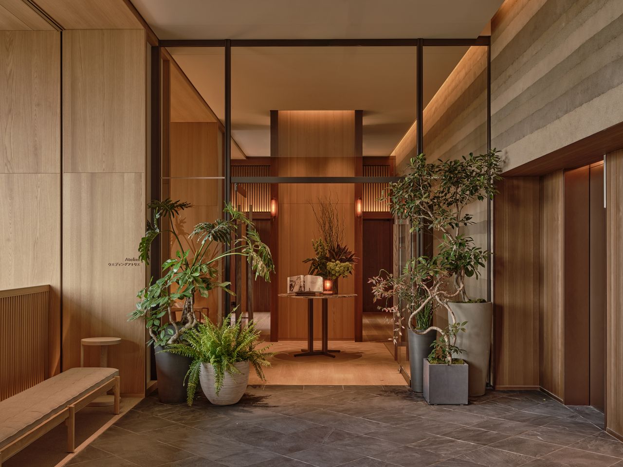 A Japanese hotel clad in soft wood and textile furnishings boasts an earthy palette accentuated by thriving planters filled with sculptural plants.