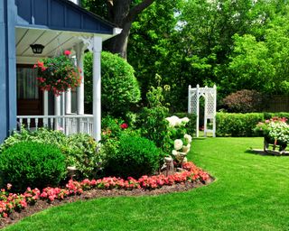 A front yard with garden edging, flowers, and traditional porch
