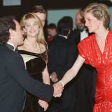 Princess Diana wearing a red dress shaking hands with Billy Crystal as Meg Ryan looks on at the 'When Harry Met Sally' premiere