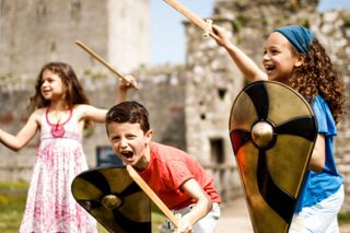 Children playing with pretend swords and shields at an English Heritage site