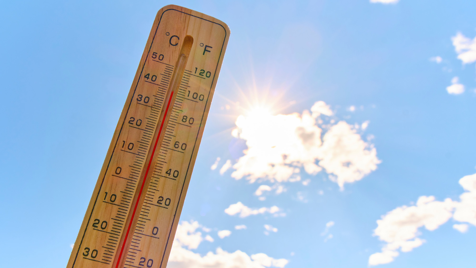 Wooden outdoor thermometer background scorching summer sun and blue sky