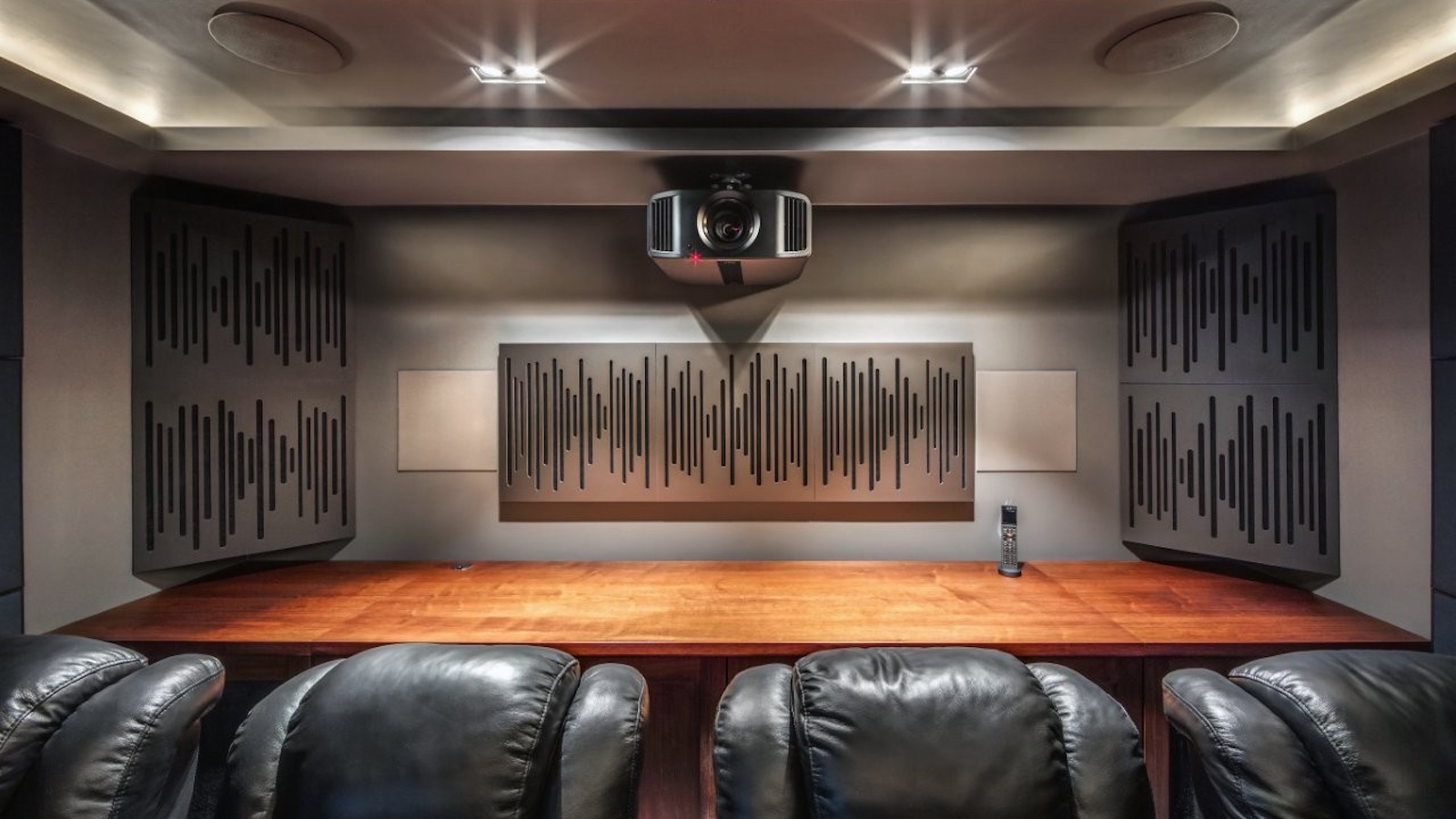 A photo of a custom-installed home cinema room featuring a 4K projector, theatre seating and clever acoustic treatment
