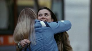 Linda Cardellini smiles while receiving a hug outside in the Freaks and Geeks series finale.