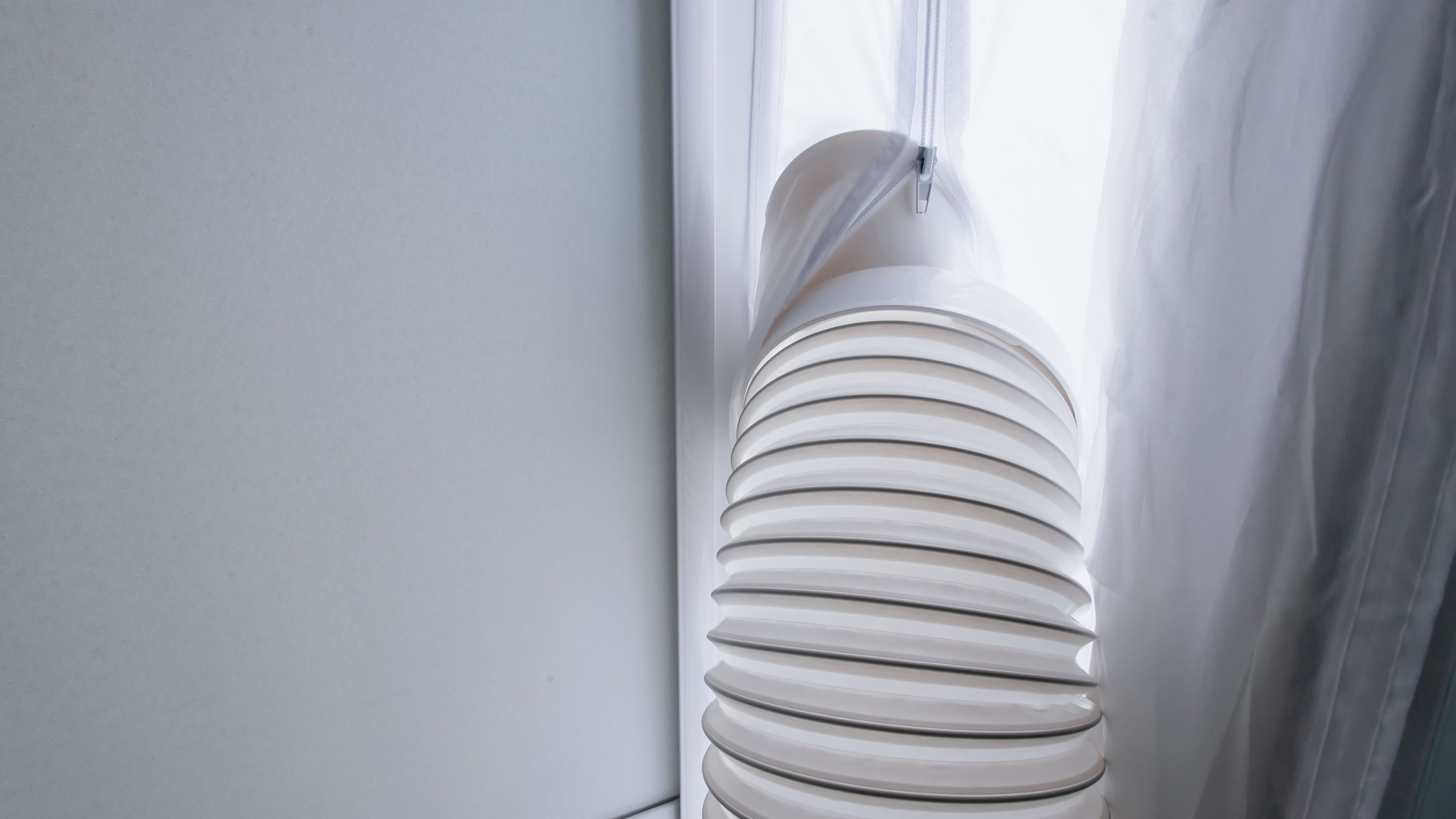 Portable air con exhaust hose vented out of a window with a fabric window kit