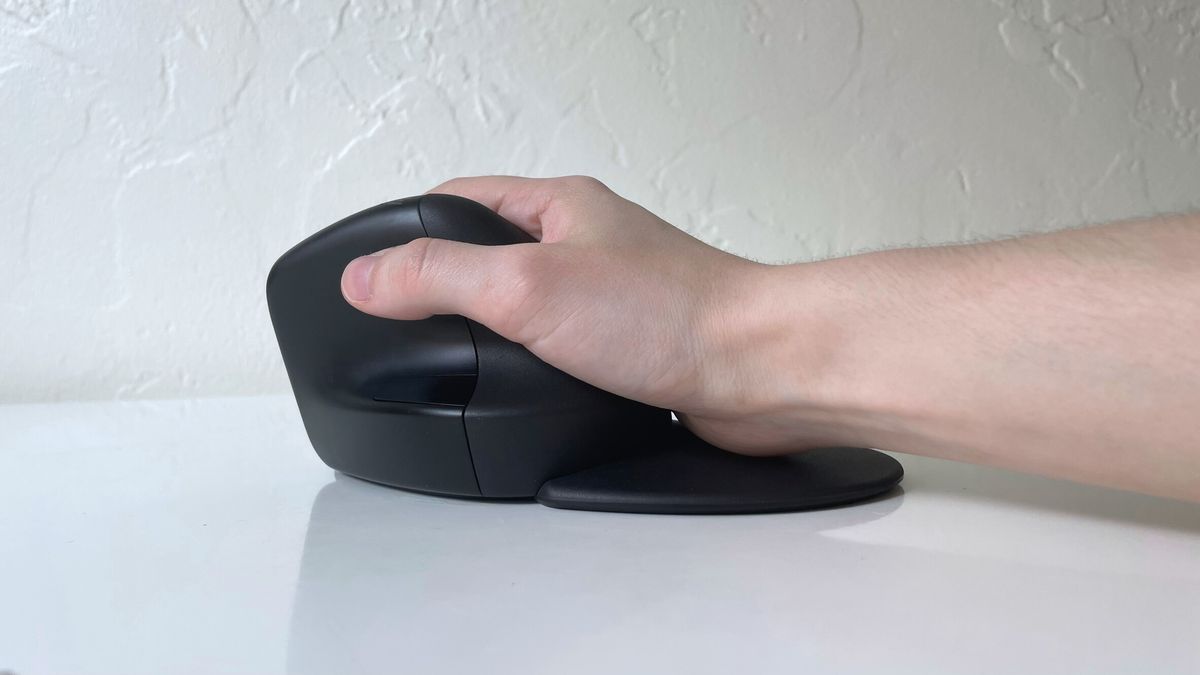 The HP 925 ergonomic vertical mouse in a user&#039;s hand on a white desk