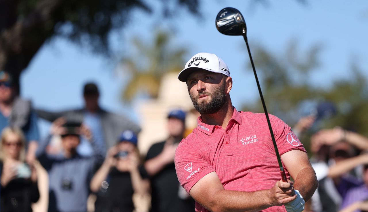 Rahm watches his tee shot while holding his driver