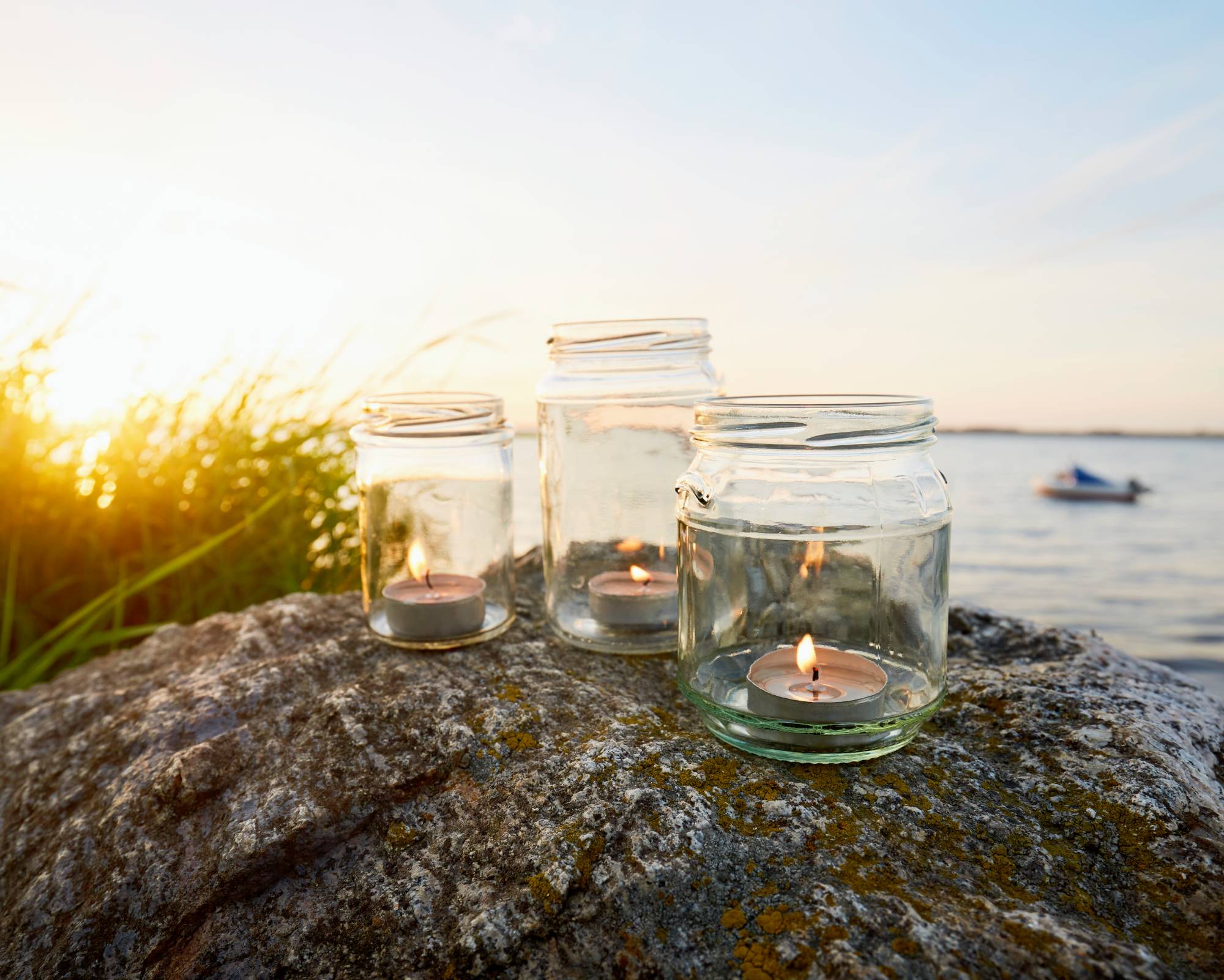 Mason jars with candles near lake