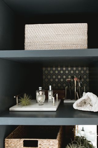 bathroom shelving unit with make up shelf in gray, basket and plants on one shelf