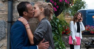 Behind the Woolpack, Holly Barton and Jai Sharma are kissing when they hear Megan Macey approaching. They jump apart but is their secret out in Emmerdale.