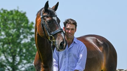 Harry Meade standing with a bay horse at his shoulder