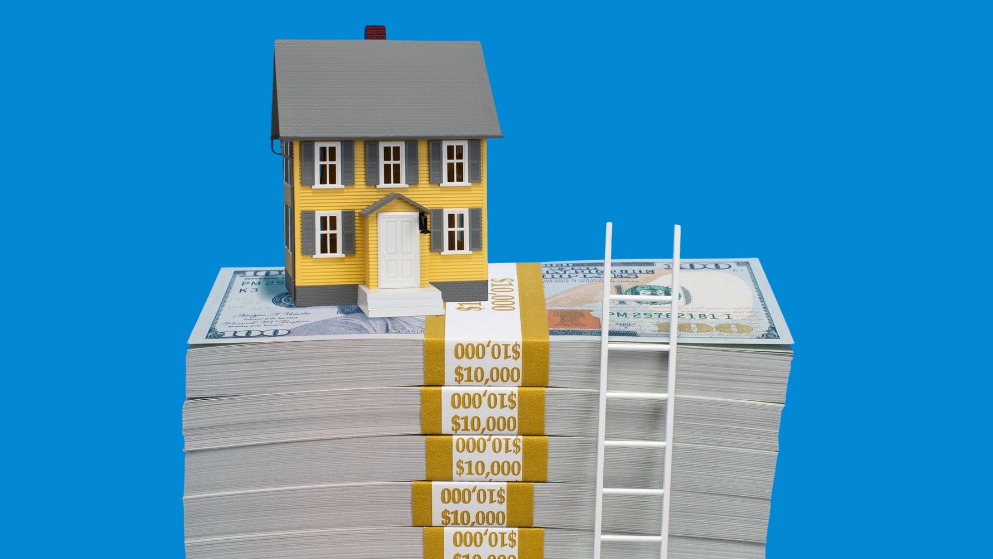 A small model home on top of a stack of $100 bundles. With a tiny ladder on the right side.