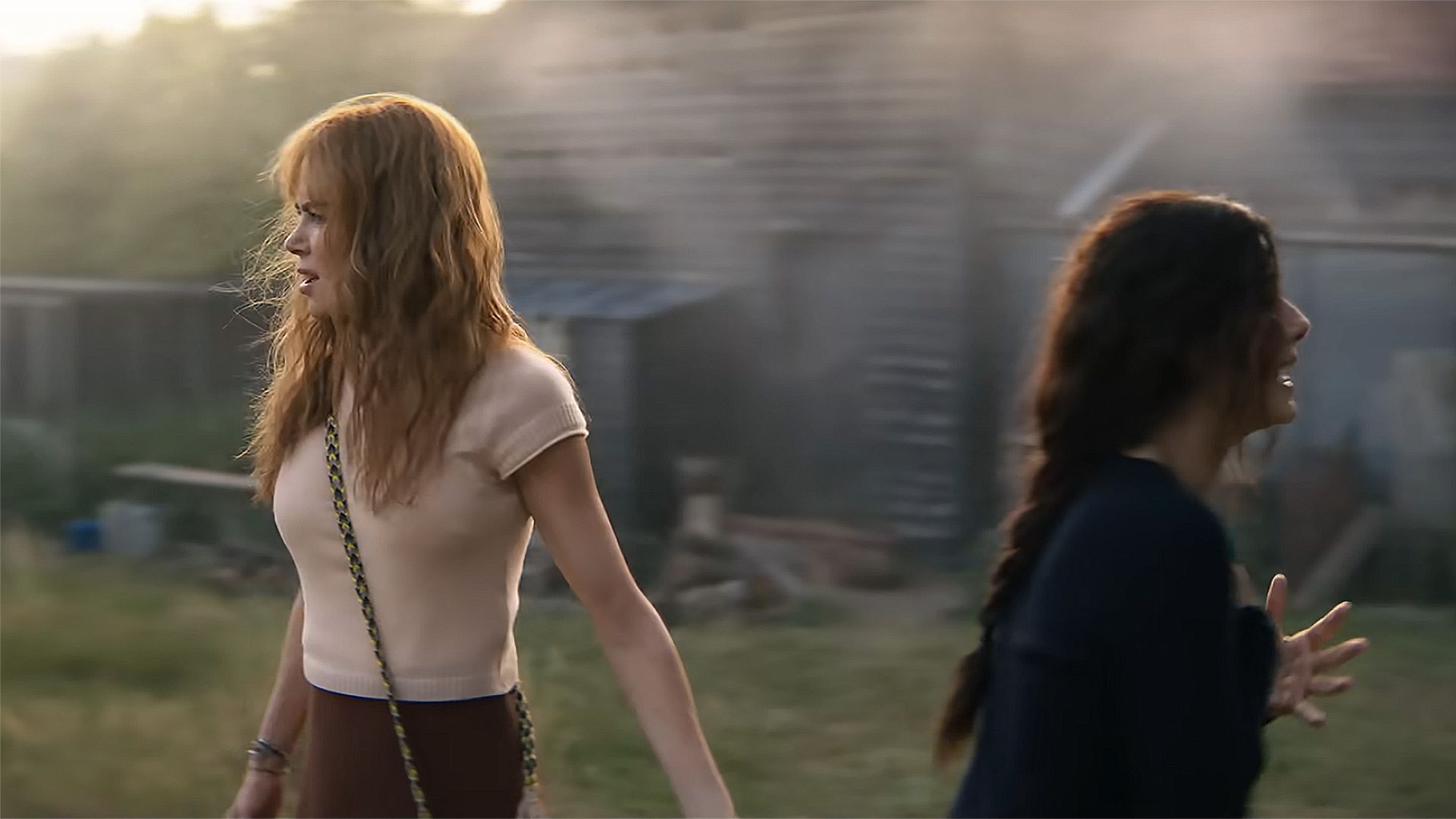 Nicole Kidman and Sandra Bullock stand back-to-back out in English nature in Practical Magic 2 scene.